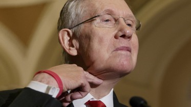 Senate Majority Leader Harry Reid of Nev. makes a cutting gesture across his neck, referencing House Oversight Committee Chairman Rep. Darrell Issa, R-Calif., who caused an uproar last week when he made the same gesture to order microphones cut as the top Democrat on his panel was trying to speak about the Internal Revenue Service scandal over targeting of conservative political groups,  Tuesday, March 11, 2014, during a news conference on Capitol Hill in Washington, Tuesday, March 11, 2014. Reid said that he thought the accusations of IRS misdeeds deserved answers. (AP Photo/J. Scott Applewhite)